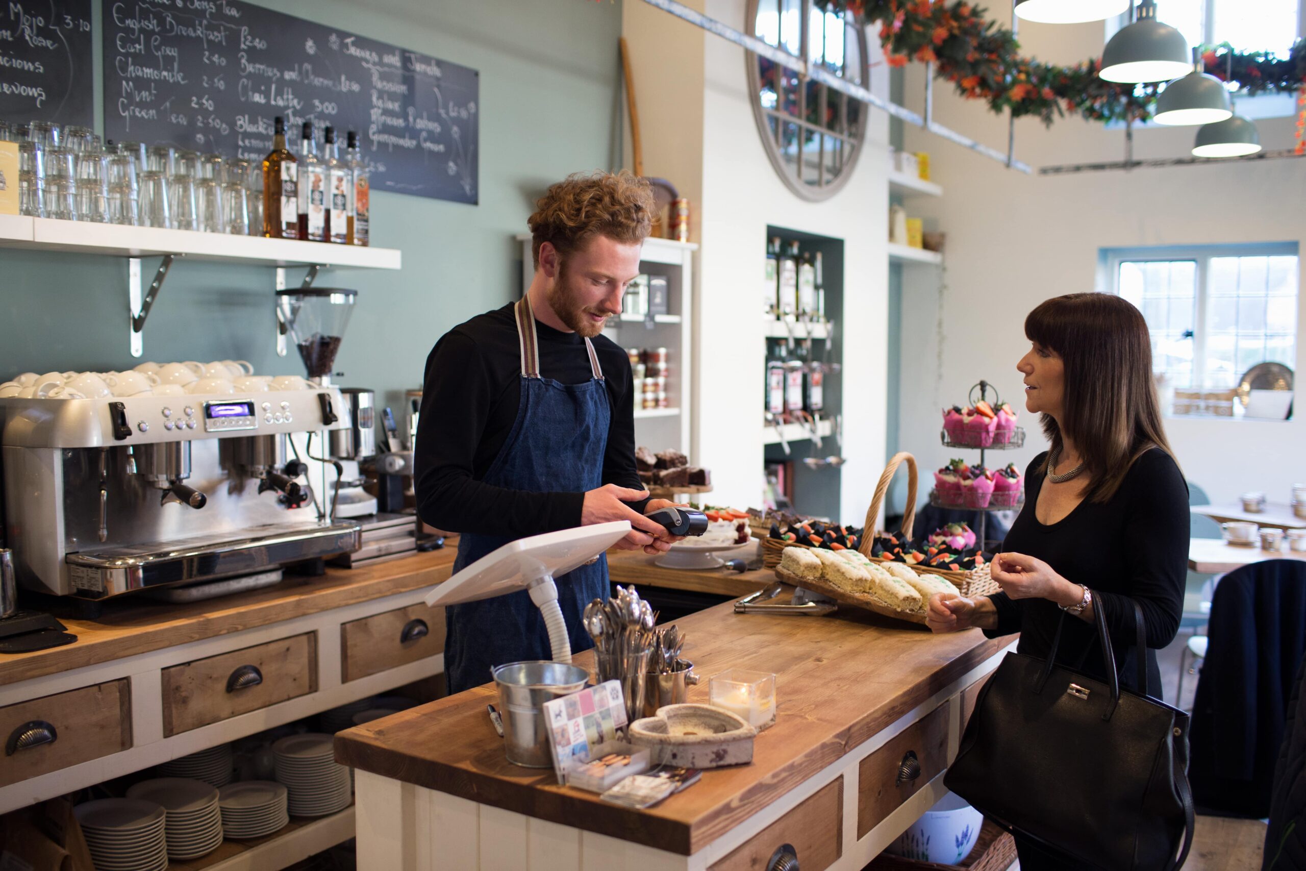 Customer pays her tab in a coffee shop. Barrista uses a wireless POS system connected by high speed Kinetic Business internet