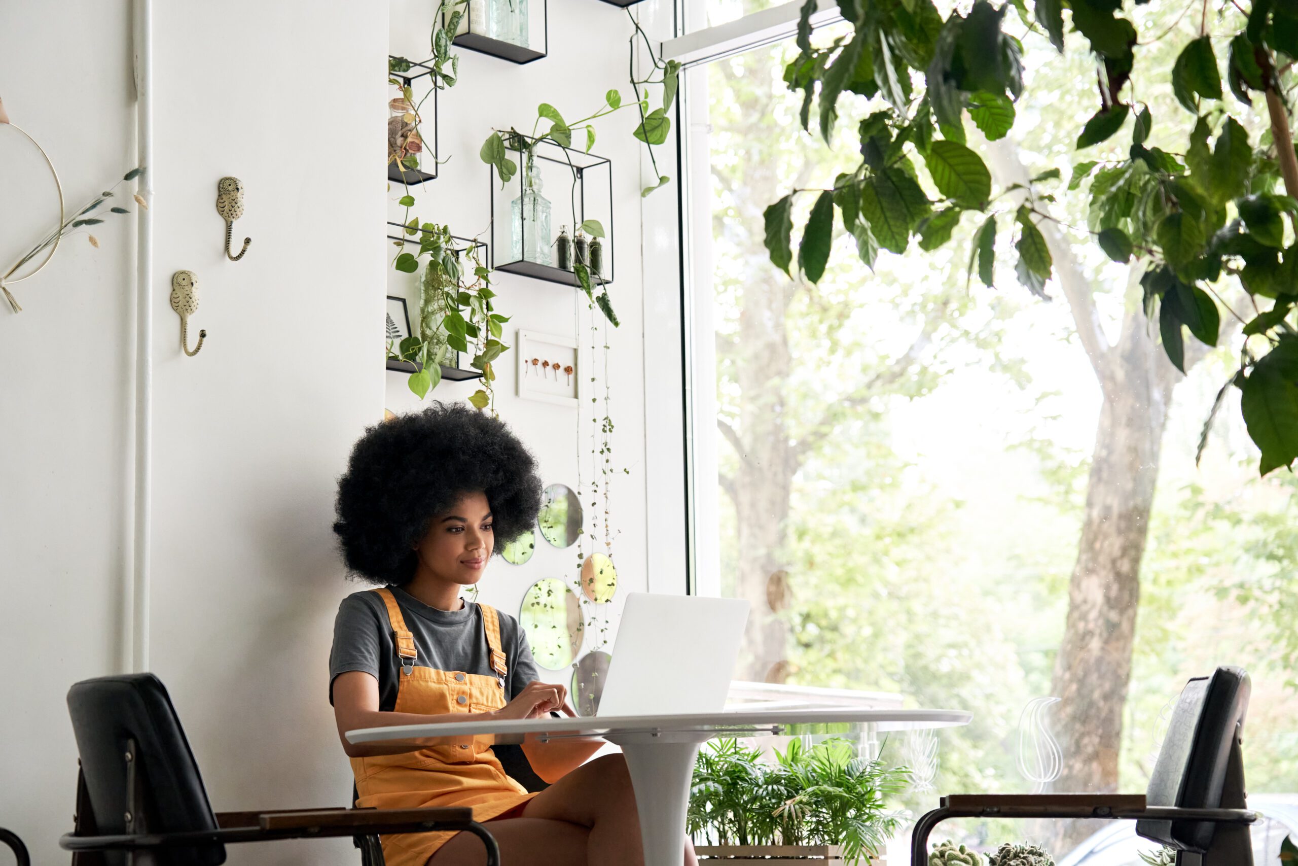 Student with afro hair in a sunny cafe uses her laptop connected to the internet by WIFI provided by Kinetic Business.