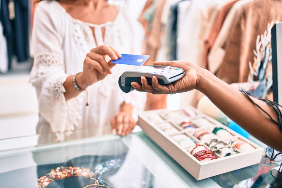 Woman paying for her purchase using credit card on a handheld point of sale system at a clothing store that has Kinetic Business Gig fiber internet.