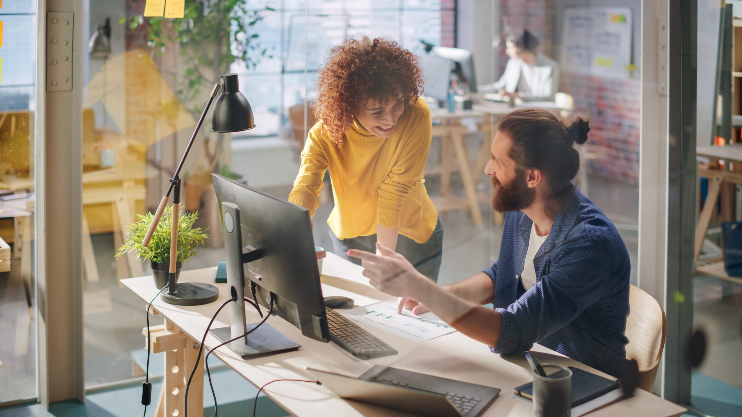 Employees in a creative agency discuss a project on a computer accessing the internet via Kinetic Business Fiber Internet