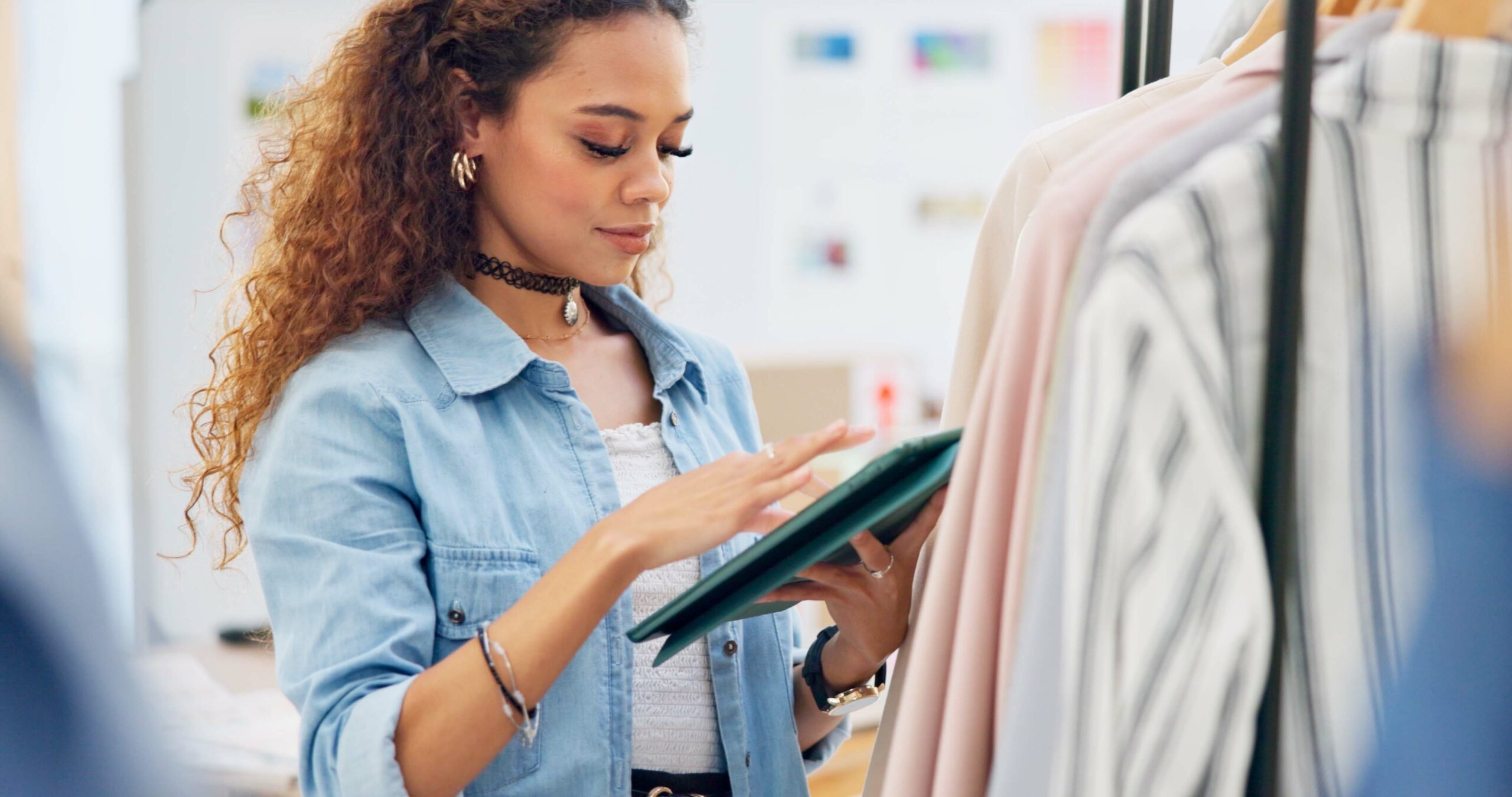 Retail store clerk uses her wireless tablet to check price on clothing. Fiber-backed internet service by Kinetic Business