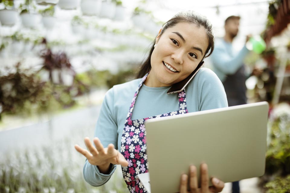 Small greenhouse business owner consults with a Kinetic Business internet specialist on her cell phone.