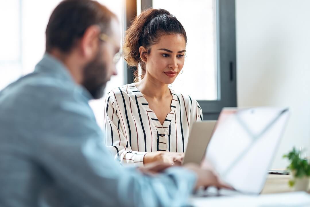 Man and woman collaborating in a small business setting using laptops powered by Kinetic Business Fiber Internet.