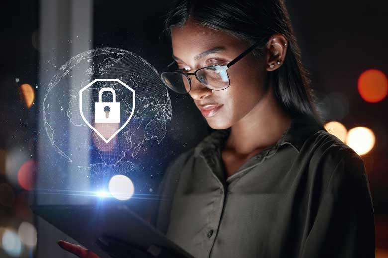 depiction of small business cybersecurity shows closeup of a woman at night wearing glasses reflecting the glow of a computer monitor with a lock icon globe diagram superimposed in the foreground